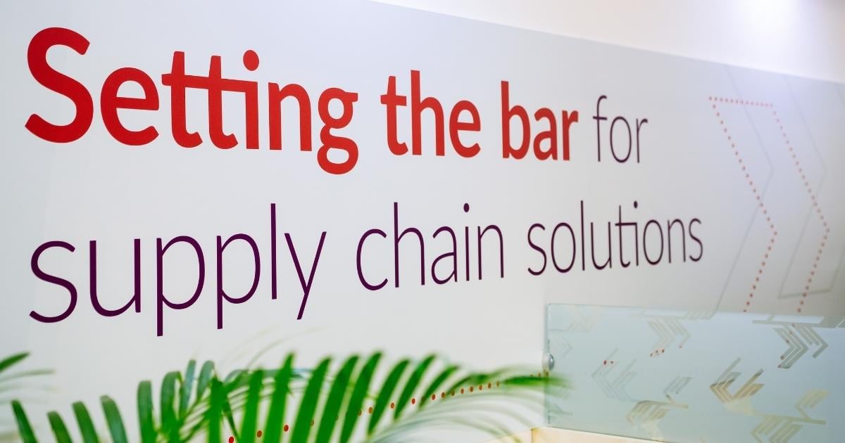 Image displaying a large format graphic design element from the trade show booth, stating 'Set the bar for supply chain solutions', strategically placed above the booth's bar area to exemplify Velocity Electronics' brand message in a creative and engaging way