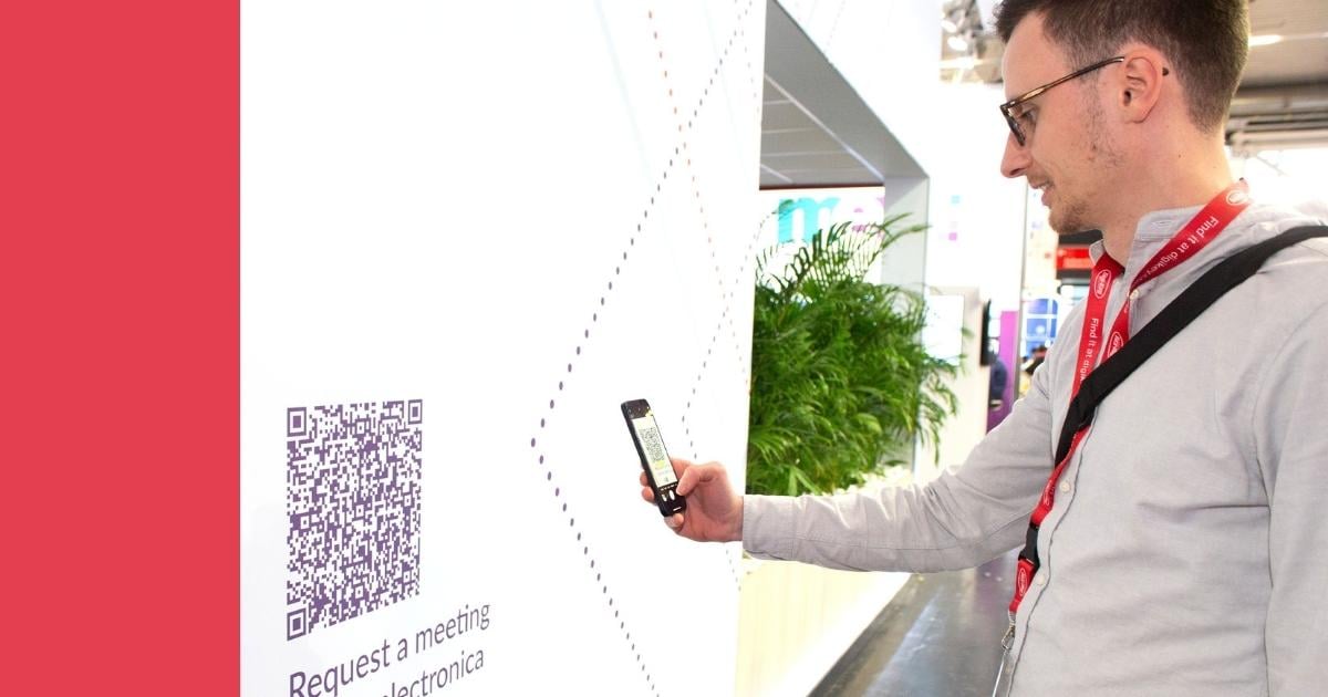 "Image showcasing an event attendee scanning a QR code at the Velocity Electronics trade show booth. This interactive element, seamlessly incorporated into the booth design, provided an efficient and user-friendly method for booking appointments and accessing additional company information.